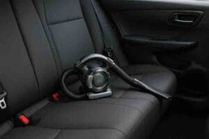 Autoimuri asetettuna auton takapenkille, esillä kompakti käsikäyttöinen malli auton sisätilojen puhdistukseen